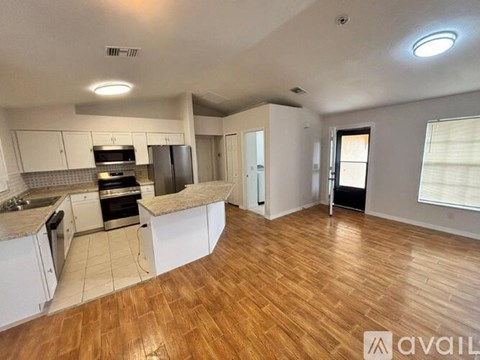 A spacious kitchen with white cabinets and a wooden floor.