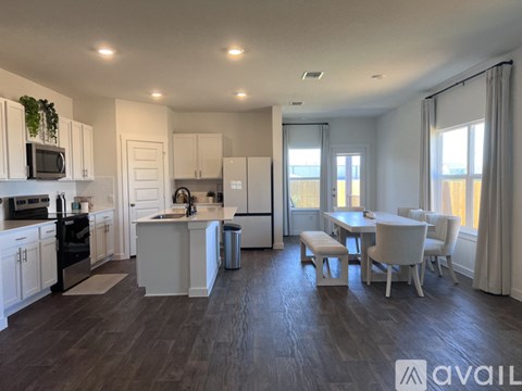 A modern kitchen with white cabinets and a dining area with white chairs.