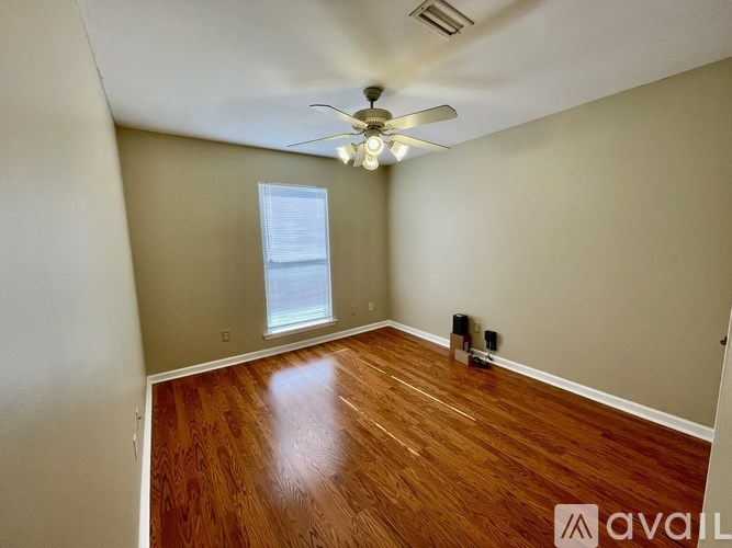 A room with a ceiling fan and wooden flooring.