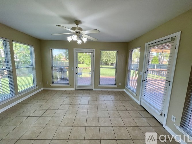 A room with a ceiling fan and sliding glass doors.