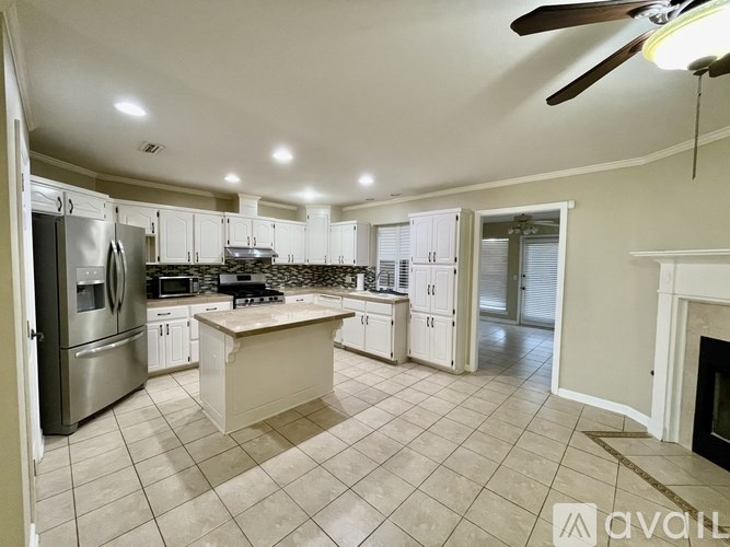 A spacious kitchen with a refrigerator, microwave, oven, and a fireplace.