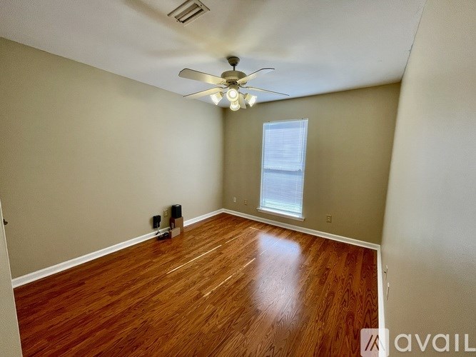 A room with a ceiling fan and wooden flooring.