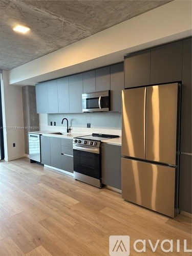 A kitchen with a stainless steel refrigerator and wooden flooring.