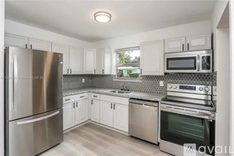 A kitchen with a stainless steel refrigerator, microwave, and oven.