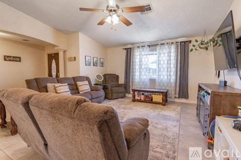 A living room with a brown couch and a ceiling fan.