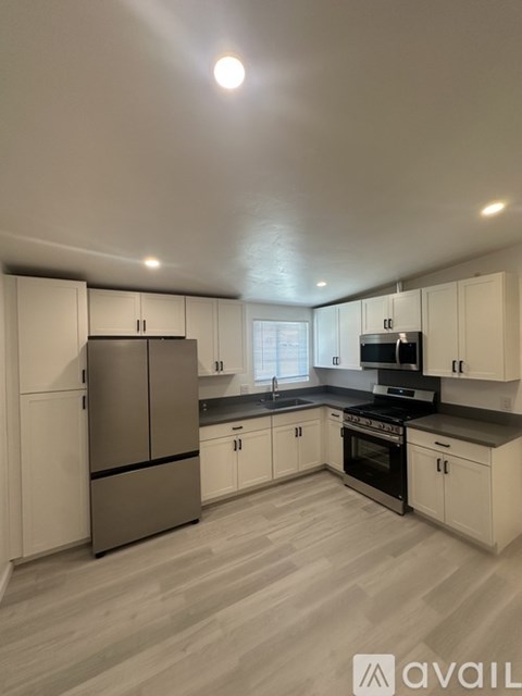 A kitchen with white cabinets and a wooden floor.