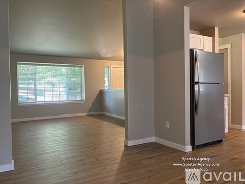 A kitchen with a refrigerator and a window with blinds.