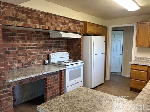 A kitchen with a brick wall and a white stove top oven.