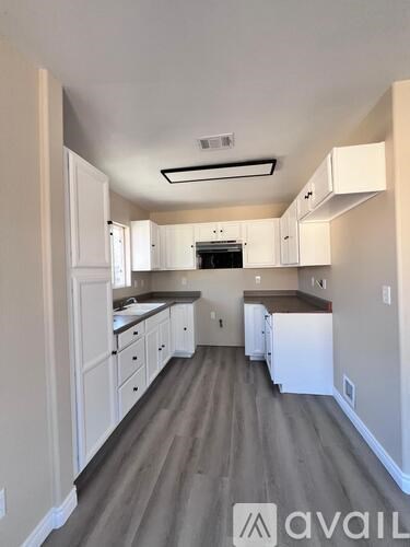 A kitchen with white cabinets and a grey floor.