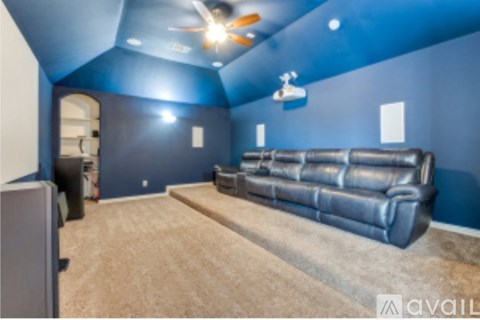A living room with a black leather couch and a ceiling fan.