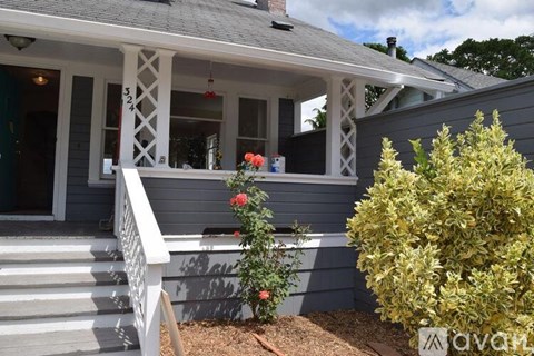 A house with a porch and a bush in front.
