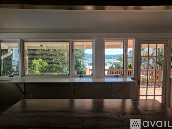 A room with a table in front of a window with a view of the water.