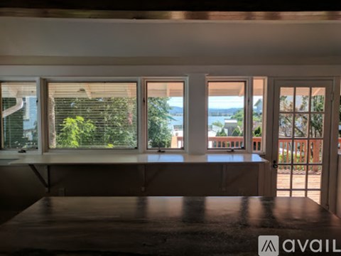 A room with a table in front of a window with a view of the water.