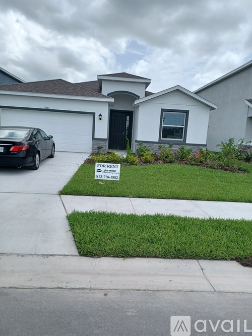 A house with a car parked in front and a for rent sign.