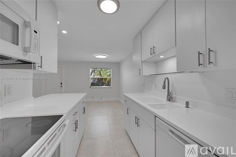 A modern kitchen with white cabinets and appliances.