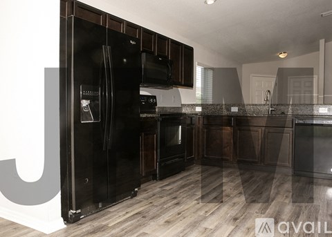 A modern kitchen with dark wood cabinets and a black refrigerator.