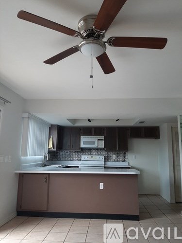 A kitchen with brown cabinets and a ceiling fan.