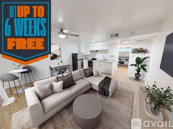 A modern living room with a sofa, a coffee table, and a kitchen area in the background.