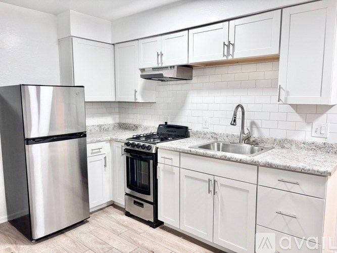 A kitchen with white cabinets and a stainless steel refrigerator.