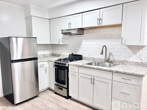 A kitchen with white cabinets and a stainless steel refrigerator.