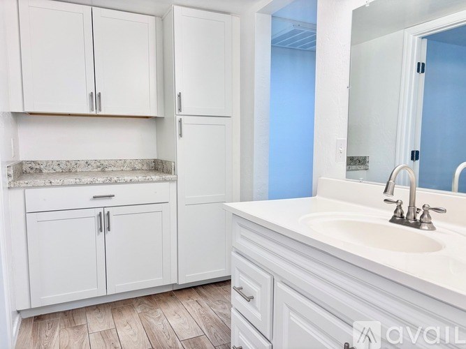 A bathroom with white cabinets and a marble countertop.
