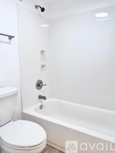 A white toilet sits next to a white bathtub in a bathroom.