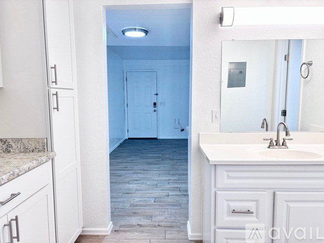 A bathroom with a sink, mirror, and a door.