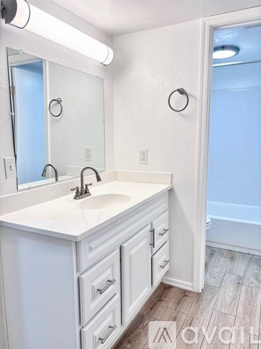 A white bathroom with a sink and mirror.