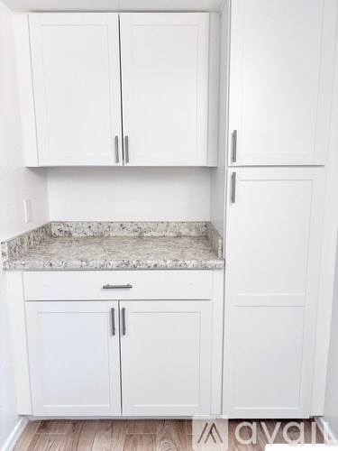 A kitchen with white cabinets and a granite countertop.