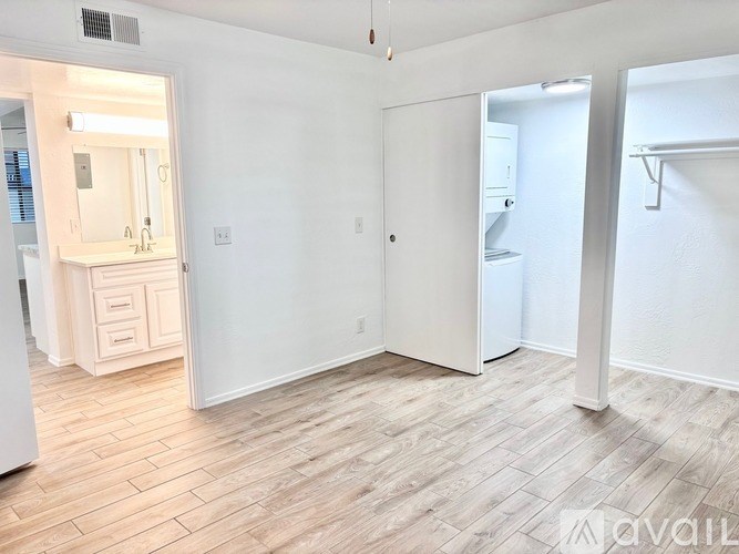 A white room with a wooden floor and a white door.