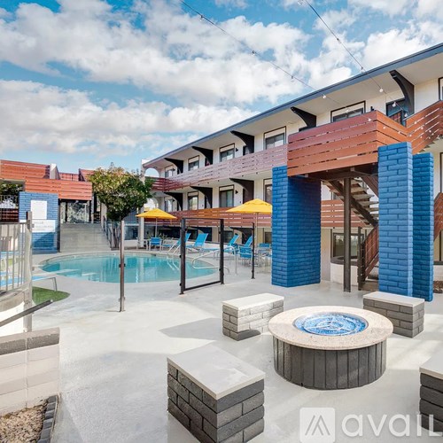 A pool area with a hot tub and lounge chairs.
