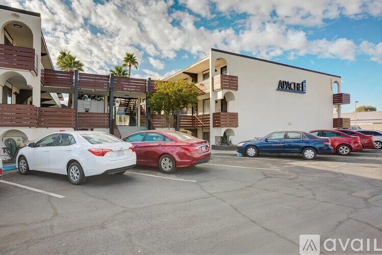 A white car is parked in front of a building with the word "Apache" on it.
