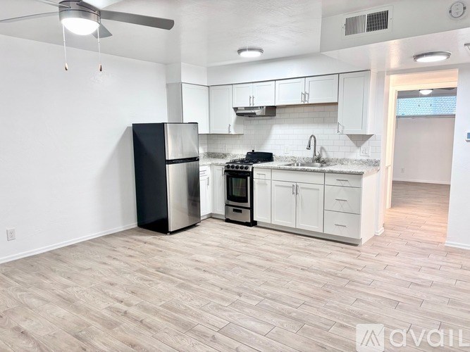 A kitchen with a black refrigerator, stove, and white cabinets.