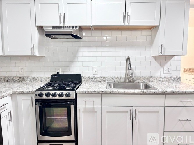 A kitchen with a black stove top oven and white cabinets.