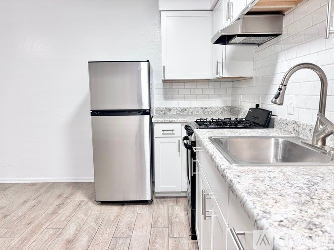 A modern kitchen with a stainless steel refrigerator, a stove, and a sink.