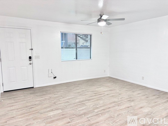 A room with a white door, a window with blinds, and a ceiling fan.