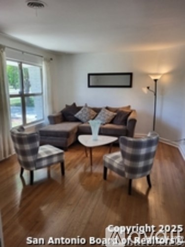 A living room with a grey couch, two chairs and a table.