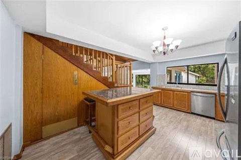 A kitchen with wooden cabinets and a stainless steel refrigerator.