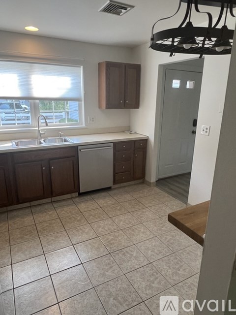 A kitchen with brown cabinets and a grey door.