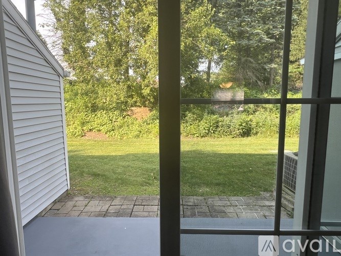 A view from a window looking out to a green lawn and trees.