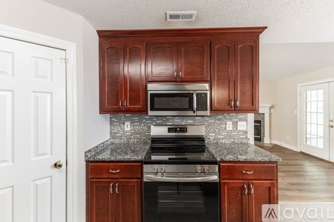 A kitchen with dark wood cabinets and a granite countertop.