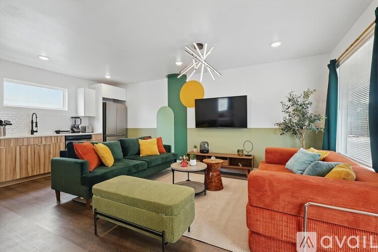 A living room with a green couch, orange couch, and a television.