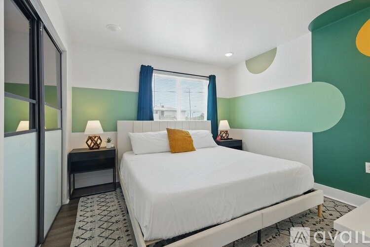 A bedroom with a white bed and a window with blue curtains.