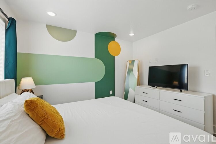 A bedroom with a bed, a television, and a mirror.