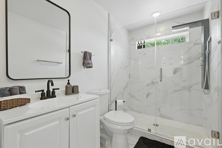 A bathroom with a white toilet, sink, and a glass shower stall.