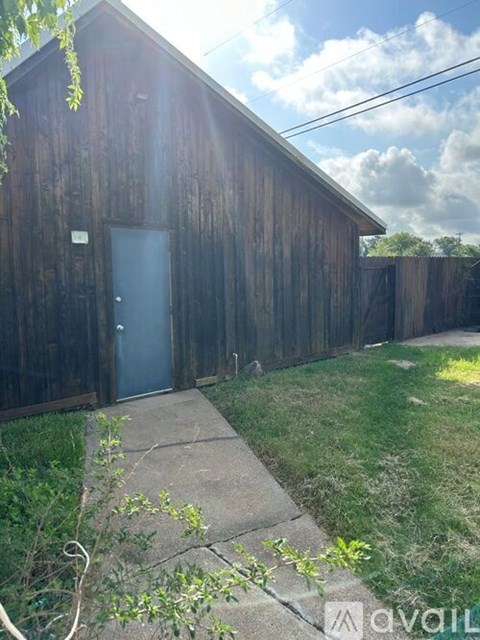 A wooden building with a door and a small garden in front.