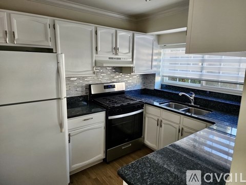 A kitchen with white cabinets and a black countertop.