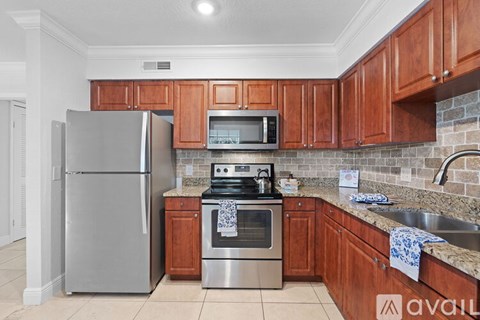 A kitchen with wooden cabinets and a stainless steel refrigerator.