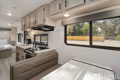 A modern kitchen with a stove top oven and a window overlooking a wooded area.
