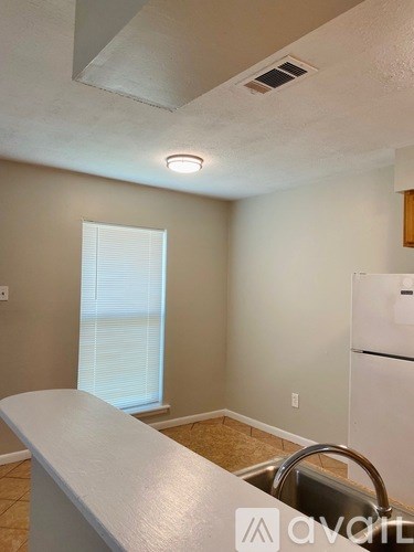 A kitchen with a white counter top and a white fridge.